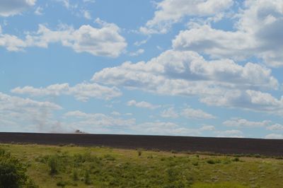 Scenic view of grassy field against cloudy sky