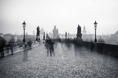 Bridge over river by buildings against sky