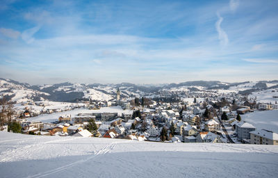 Aerial view of townscape by snowcapped mountain against sky