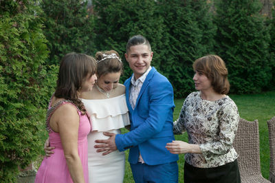 Smiling groom touching stomach of bride while standing amidst guest during wedding