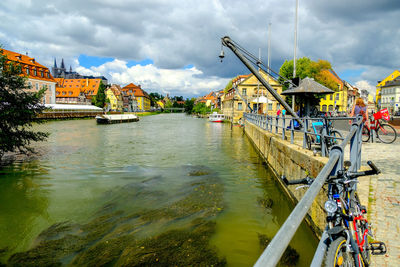 Scenic view of river by buildings against sky