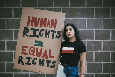 Portrait of woman standing against brick wall