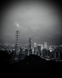 Illuminated buildings in city against sky at night