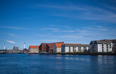 River by buildings against blue sky