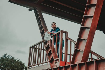 Low angle portrait of teenage boy against sky