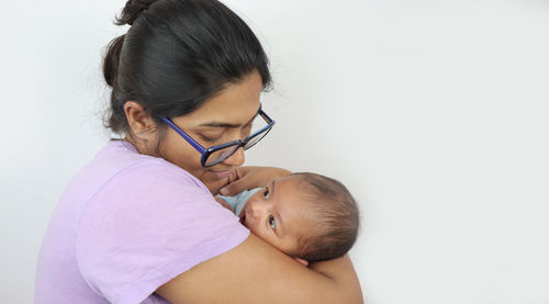 Side view of mother with baby against white background