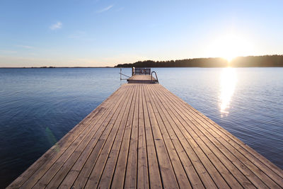 Pier over lake against sky during sunset