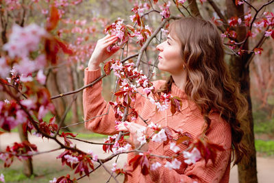 Beautiful woman standing under pink blossom sakura