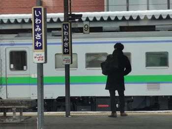 Rear view of man standing by train at railroad station