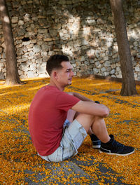 A young attractive boy in a red t-shirt posing in a park.