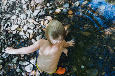 Rear view of shirtless boy in sea