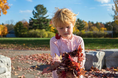 Girl playing with autumn leaves