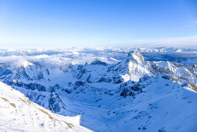 Scenic view of snowcapped mountains against blue sky