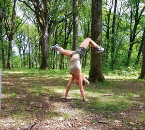 Full length side view of woman walking on road in forest