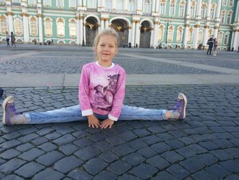 Girl sitting on sidewalk in city