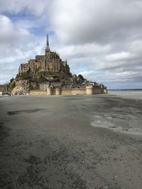 Building at beach against cloudy sky