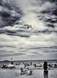 People flying over beach against sky