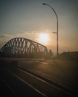 Bridge over road against sky during sunset