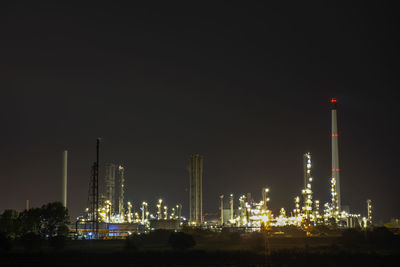 Illuminated factory against sky at night