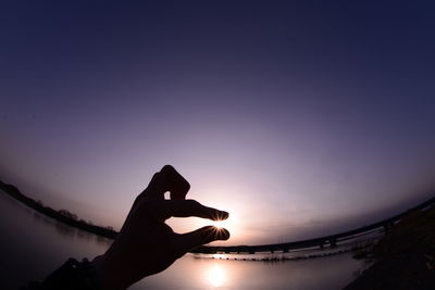 Optical illusions of person holding sun during sunset