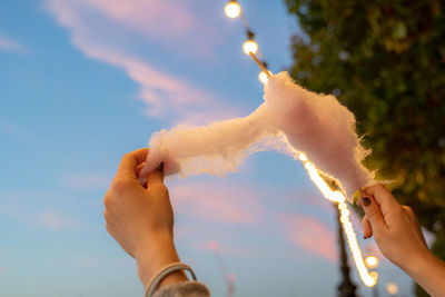 Midsection of person holding sparkler against sky