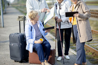 Group of positive senior people looking at map on traveling journey during pandemic