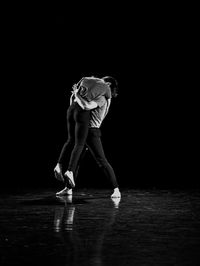 Full length of woman dancing against black background