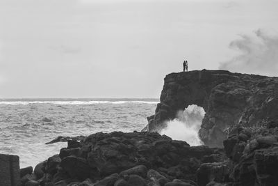 Rock formation on beach against sky