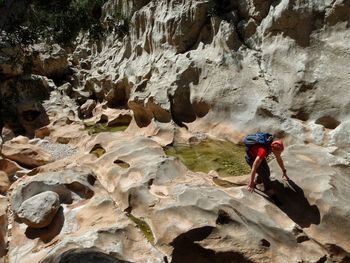 High angle view of male hiker hiking on rocks