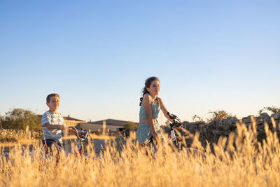 Two kids on a bike in front of a wheat field