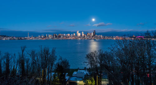 A full moon shines above the seattle skyline.