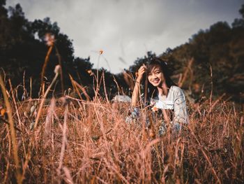 Young woman standing on field against sky