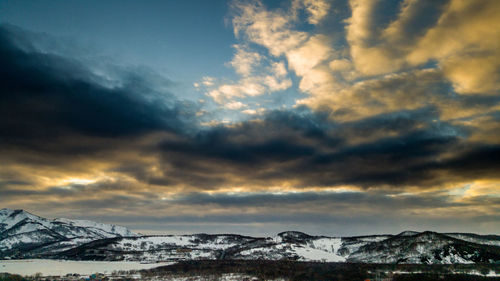 Scenic view of snowcapped mountains against dramatic sky