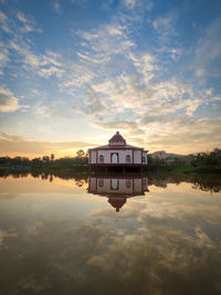 Reflection of building in lake against sky during sunset