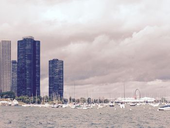 Sailboats in sea by buildings against sky