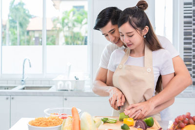 Smiling couple cutting vegetables in kitchen
