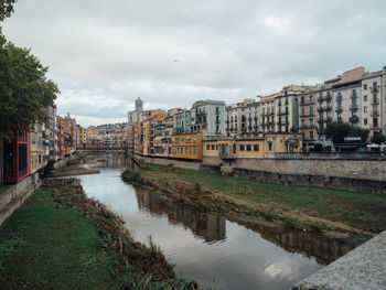 River amidst buildings in city against sky