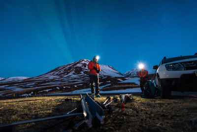 A woman getting ready to ski with mountains and northern lights