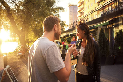 Couple having salad and water while standing on street during sunset