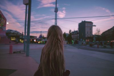 Rear view of girl with long hair on sidewalk