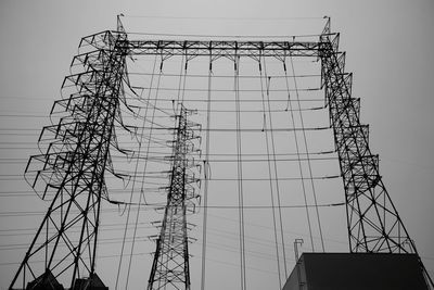 Low angle view of silhouette electricity pylon against sky