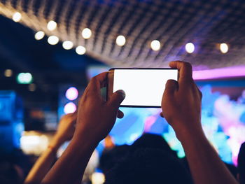 Midsection of man photographing illuminated mobile phone