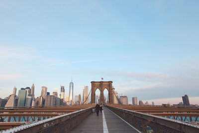 People on bridge against sky in city