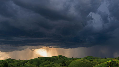 Scenic view of agricultural landscape against storm clouds