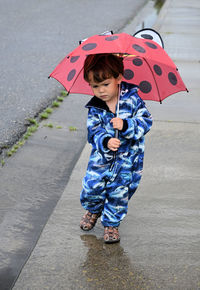 Full length of cute girl standing on wet rainy day