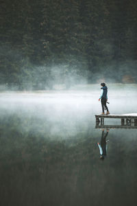 Side view of man standing on water against sky