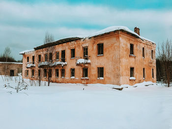 Snow covered field by buildings against sky