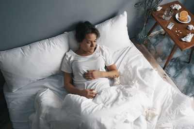 High angle view of woman lying down on bed at home