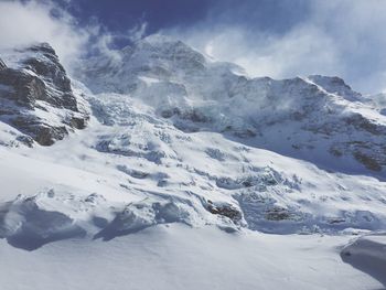 Scenic view of snow covered mountains against cloudy sky