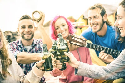 Male and female friends toasting beer bottles at beach